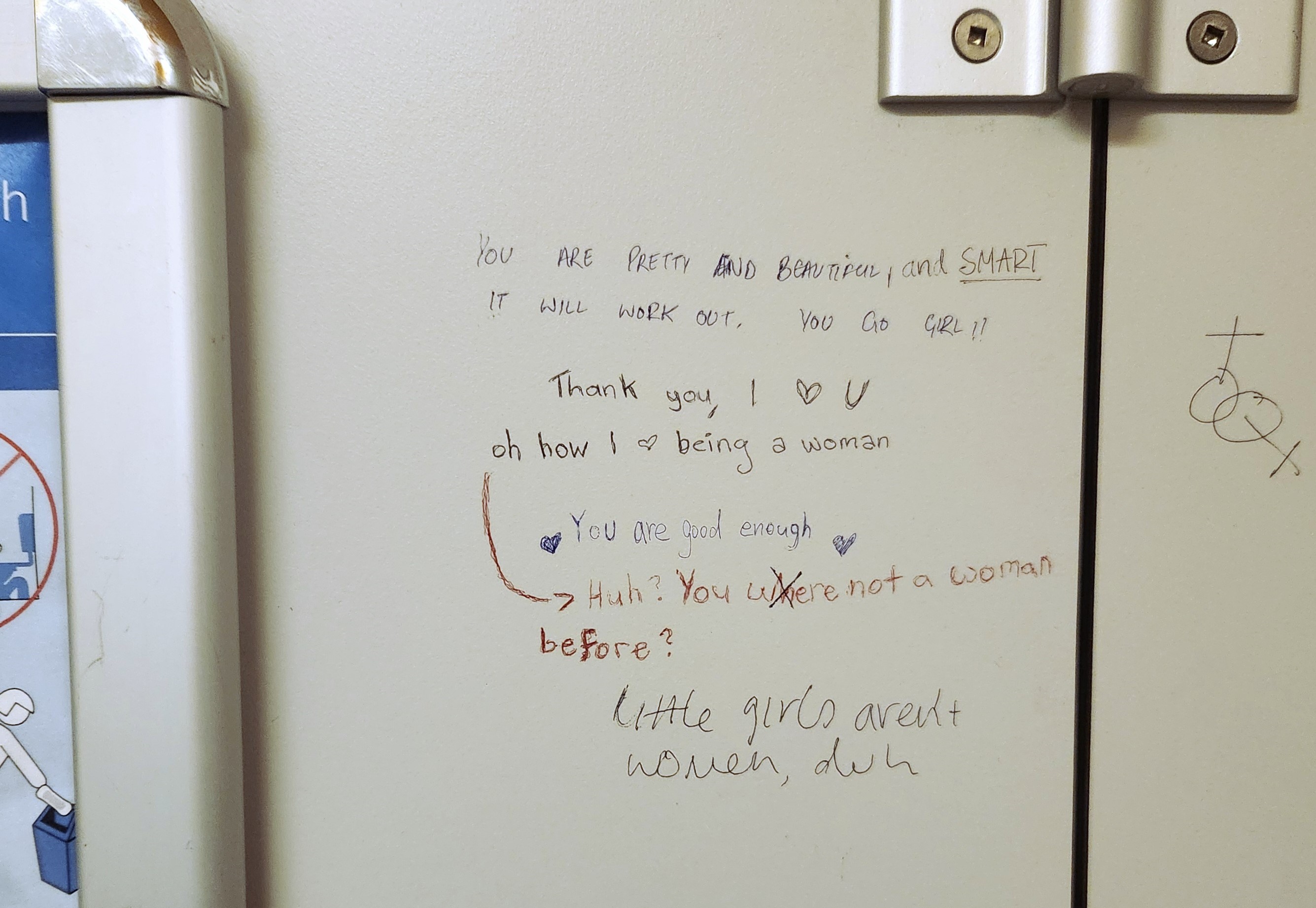 A closeup of a toilet door with words written in pen by various different people: you are pretty and beautiful and SMART. It will work out. You go girl! Thank you, I heart U. Oh how I heart being a woman. You are good enough. Huh? You were not a woman before? Little girls aren't women, duh.