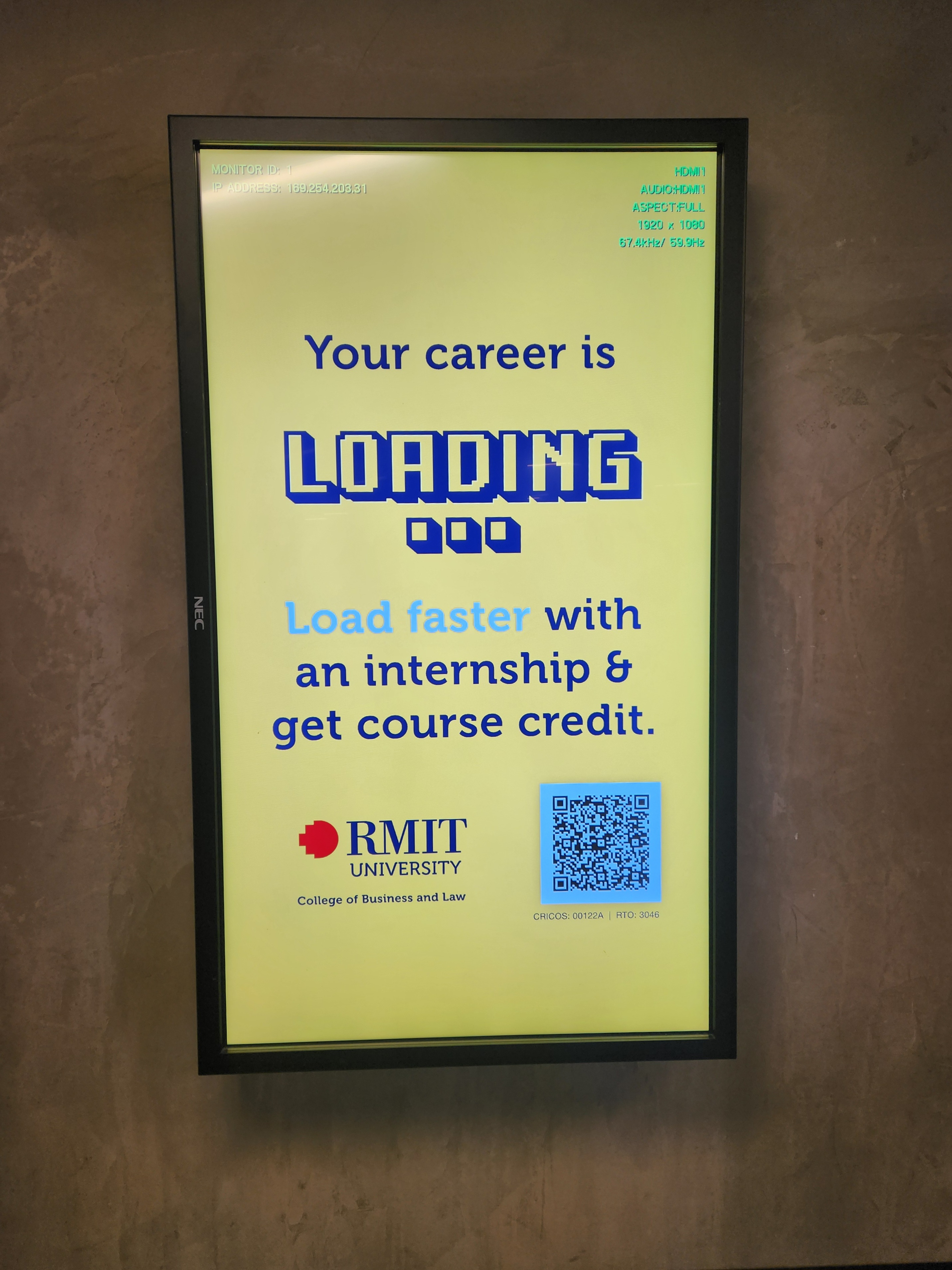 A digital poster display reading: Your career is loading. Load fast with an internship and get course credit. The RMIT logo is shown along with a QR code.